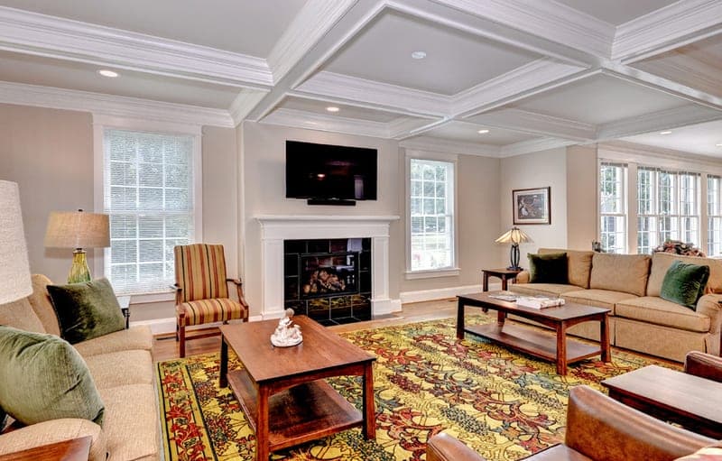 Living room with coffered ceiling, fireplace, and walls of windows