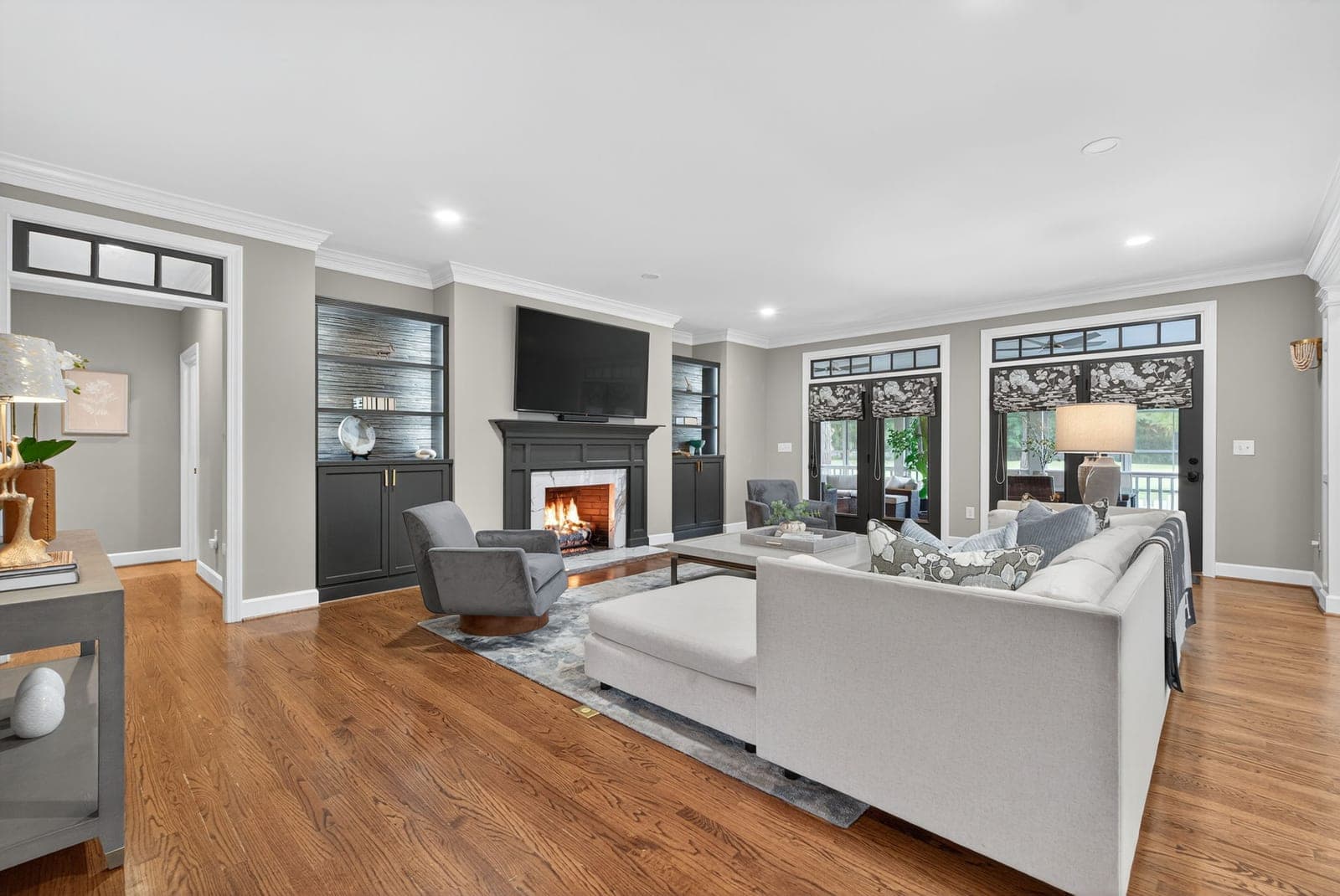 The great room at 164 Highland: fireplace flanked by built-ins, white seating, and golf-course views through the windows