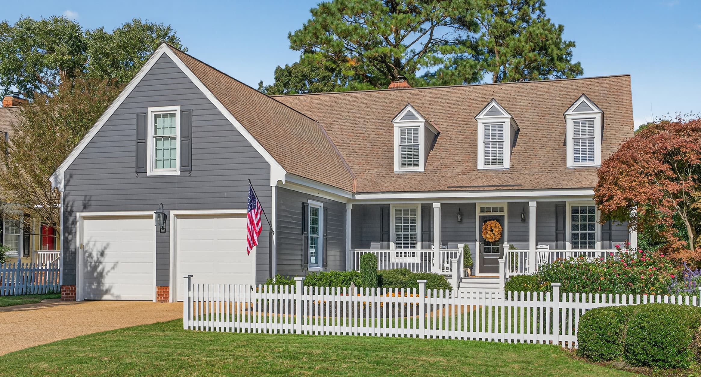 164 Highland: a gray Cape Cod home with a white picket fence and American flag, on the 18th fairway of Marsh Hawk at Ford's Colony